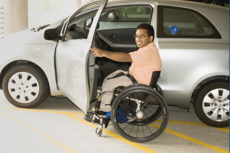 Jeune homme en fauteuil roulant s’apprêtant à monter dans une voiture